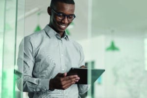 Jeune Homme souriant regardant sa tablette